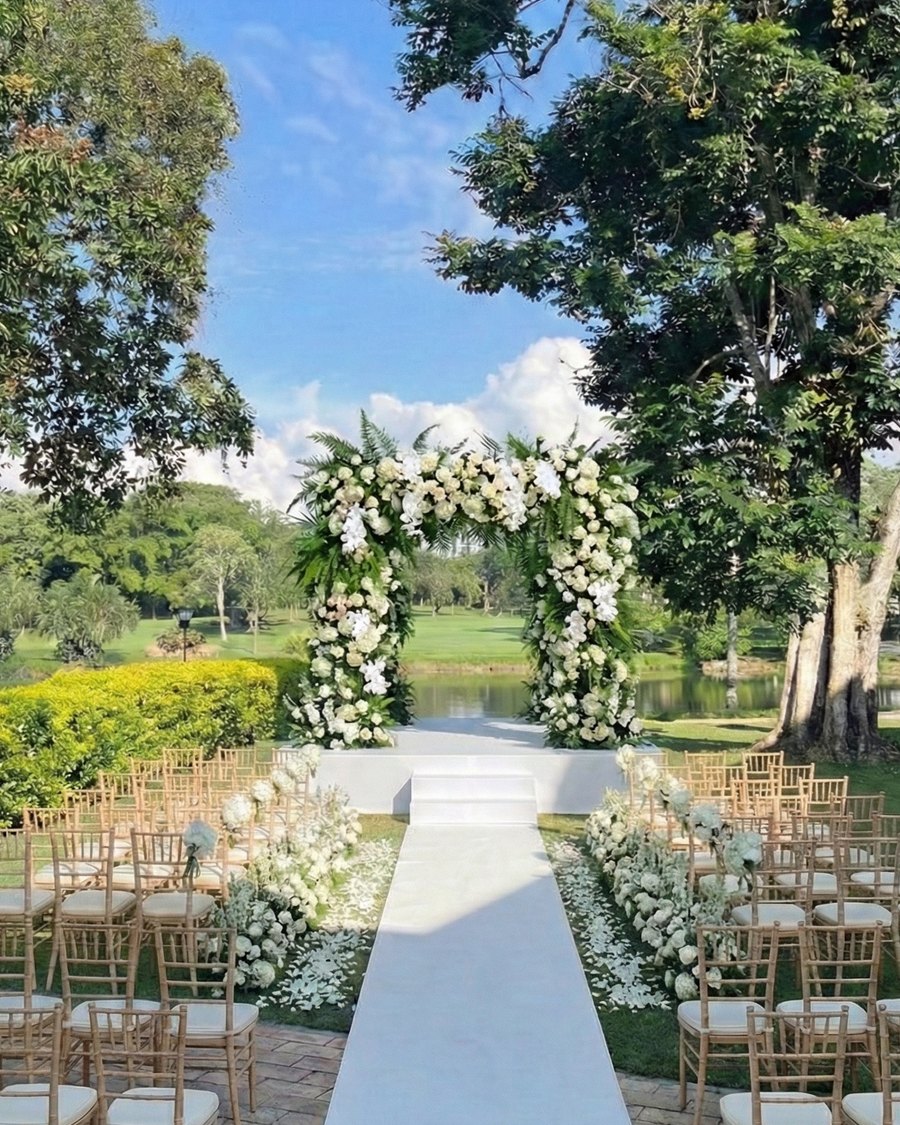El mismo campo con un arco de flores blancas, alfombra blanca y sillas doradas
